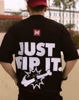 Back view of a person wearing a black, oversized BJJ t-shirt featuring the humorous white graphic "JUST RIP IT." with a logo breaking a bone, and "THEY SIGNED THE WAIVER." below.
