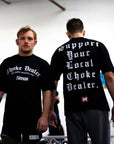 Two men wearing black t-shirts with text, standing indoors.
