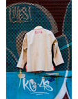 Beige BJJ Gi with embroidered back on blue graffiti wall; premium BJJ gis.