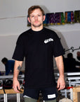 Man wearing a black bjj t-shirt with a logo in an indoor setting