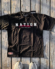 Black Nation Varsity BJJ T-shirt with oversized fit and 3D puff print design on wooden background.
