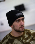 Person wearing a black Jiu Jitsu Beanies with a logo, looking to the side.