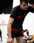 Person wearing black athletic wear with red designs in an indoor setting