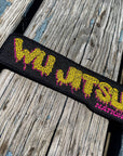 Wu Jitsu BJJ Patch with embroidered design and merrow edges on wooden surface.