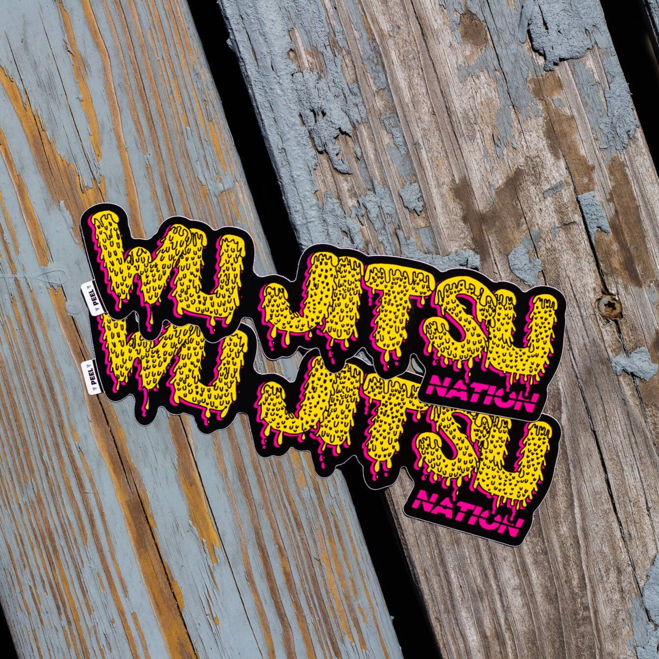 Wu Jitsu Sticker with bold yellow and pink lettering on a wooden background.
