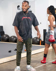 man wearing black oversized MURDER YOGA V2 BJJ t-shirt training in gym with woman boxer in red gloves