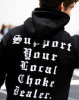 Person wearing a black bjj hoodie with text on the back in an urban setting
