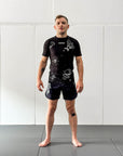 Male wearing Jiu Jitsu Dark Arts BJJ rash guard set in black on mats.