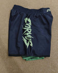 Navy shorts with green logo on a beige surface