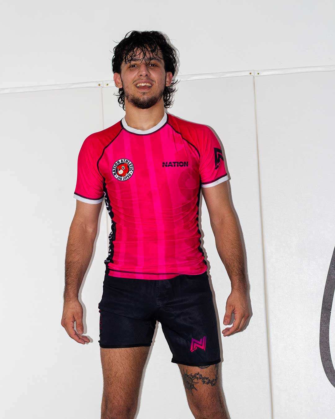 Person wearing a Laney west inspired bjj rash guard and jiu jitsu shorts with visible branding on a white background