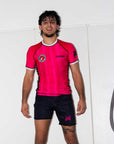 Person wearing a Laney west inspired bjj rash guard and jiu jitsu shorts with visible branding on a white background