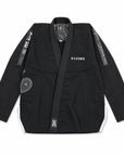 A black brazilian jiu jitsu gi jacket with white accents, featuring the brand name 'nation' on the chest, white text down one sleeve, and circular patches on the front and sleeve, laid flat against a white background.
