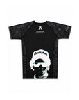A black short-sleeve bjj rash guard with a large graphic of a person wearing a white beanie and sunglasses on the front, and 'Campion' printed on the beanie. The brand 'Express Conduct' is printed in white on the upper chest.