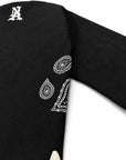 Close-up of a black Brazilian jiu jitsu kimono jacket, likely a sweater or cardigan, featuring white embroidered paisley bandana-style motifs and a white monogram letter 'A' near the shoulder.