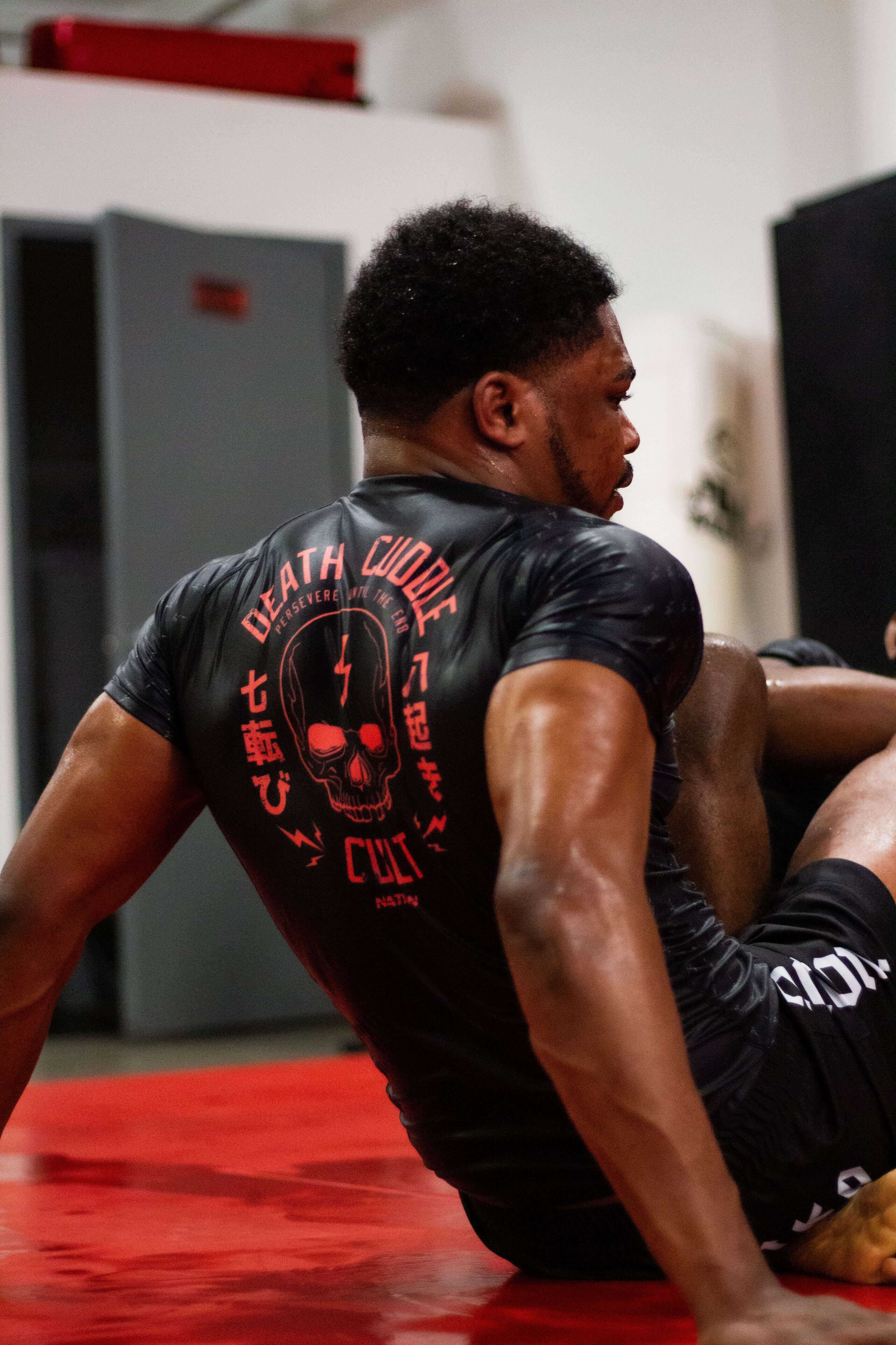 A man wearing a black rash guard with a logo at the back