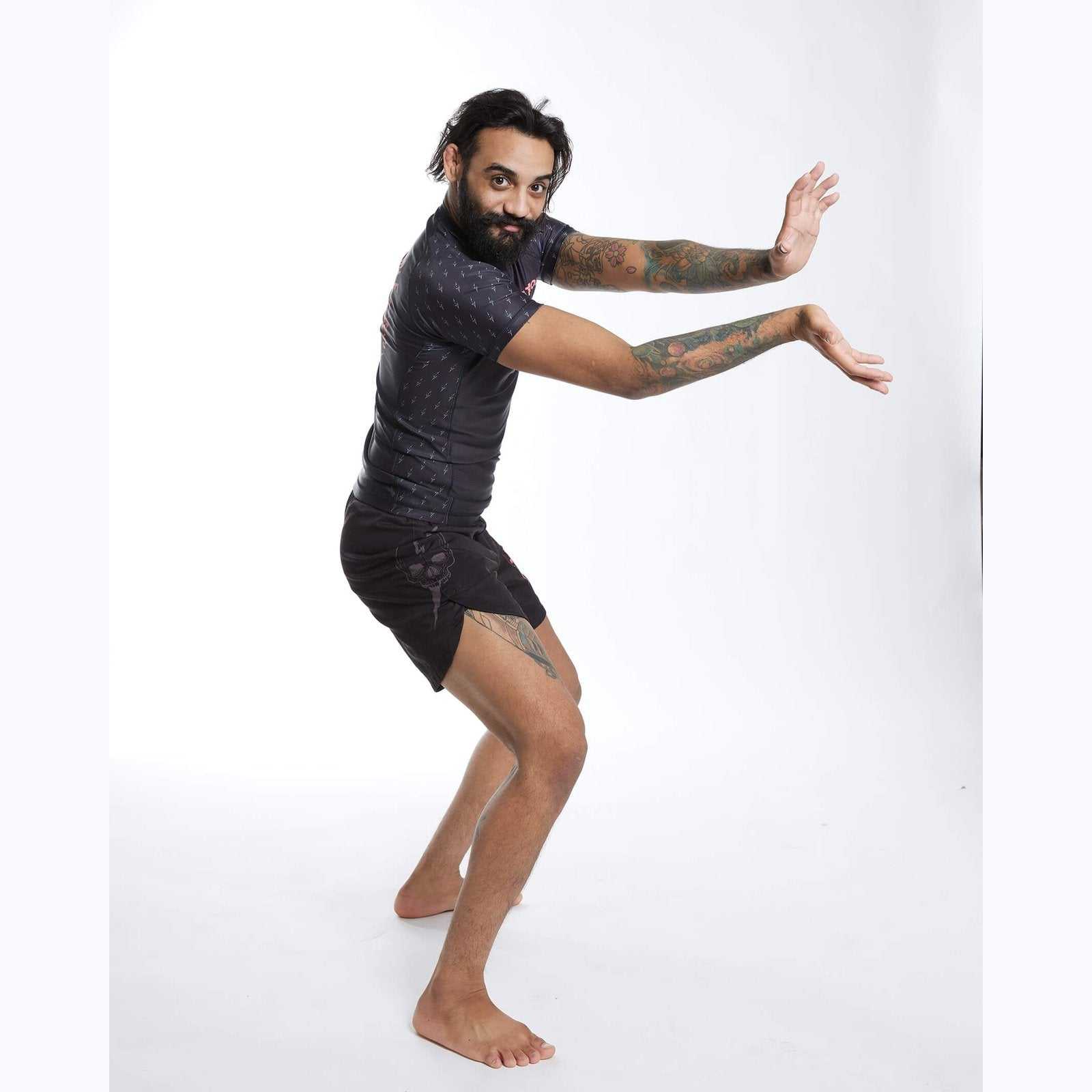 A man wearing a rash guard and shorts