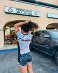 Woman wearing Rising Dragon BJJ Nogi Set rash guard and shorts standing outside Peerless Jiu Jitsu gym