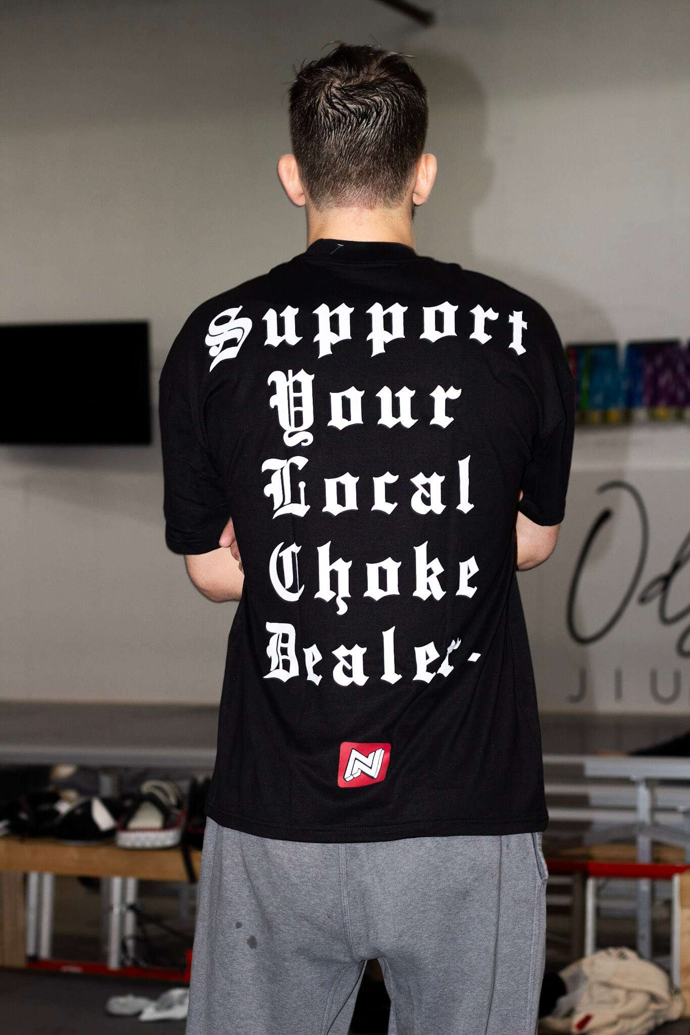 Person wearing a black t-shirt with text on the back in an indoor setting