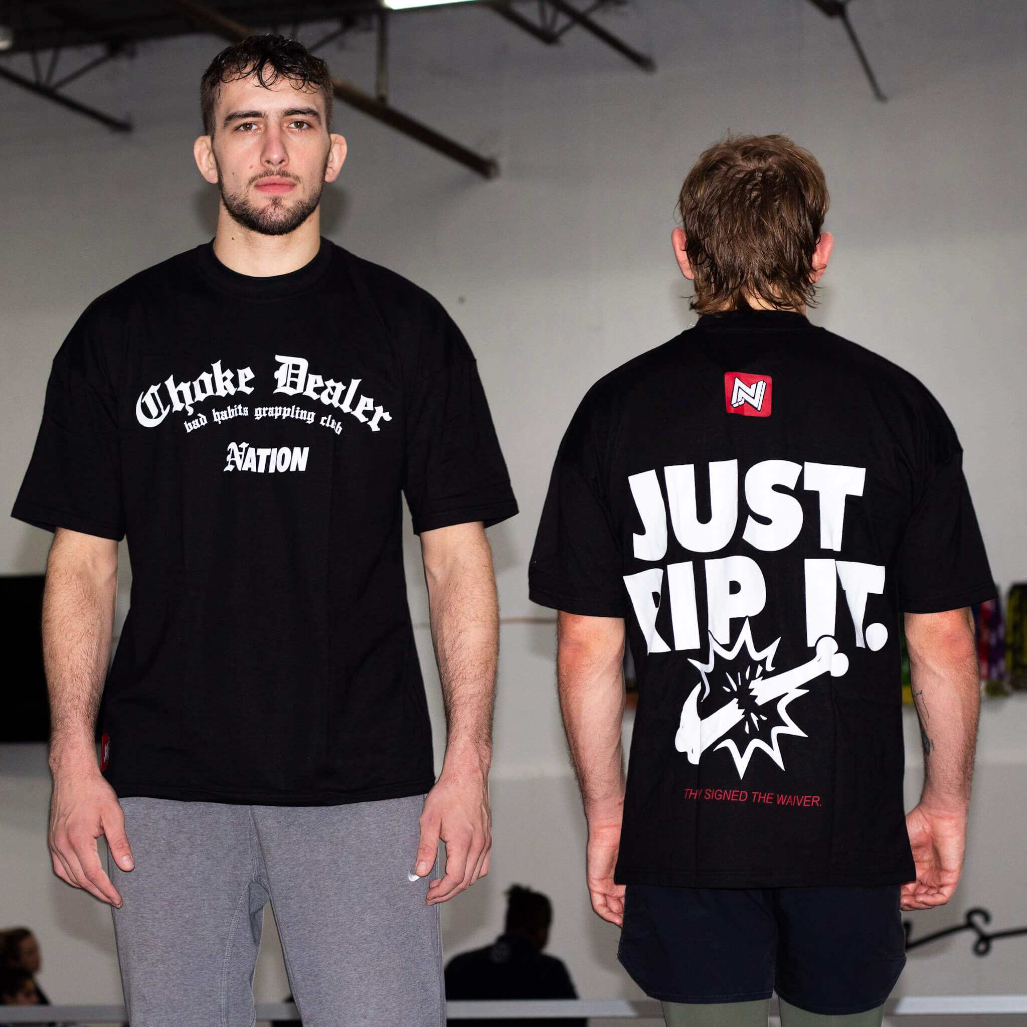 Two men wearing black bjj t-shirts with text and graphics, one facing forward and one facing backward.