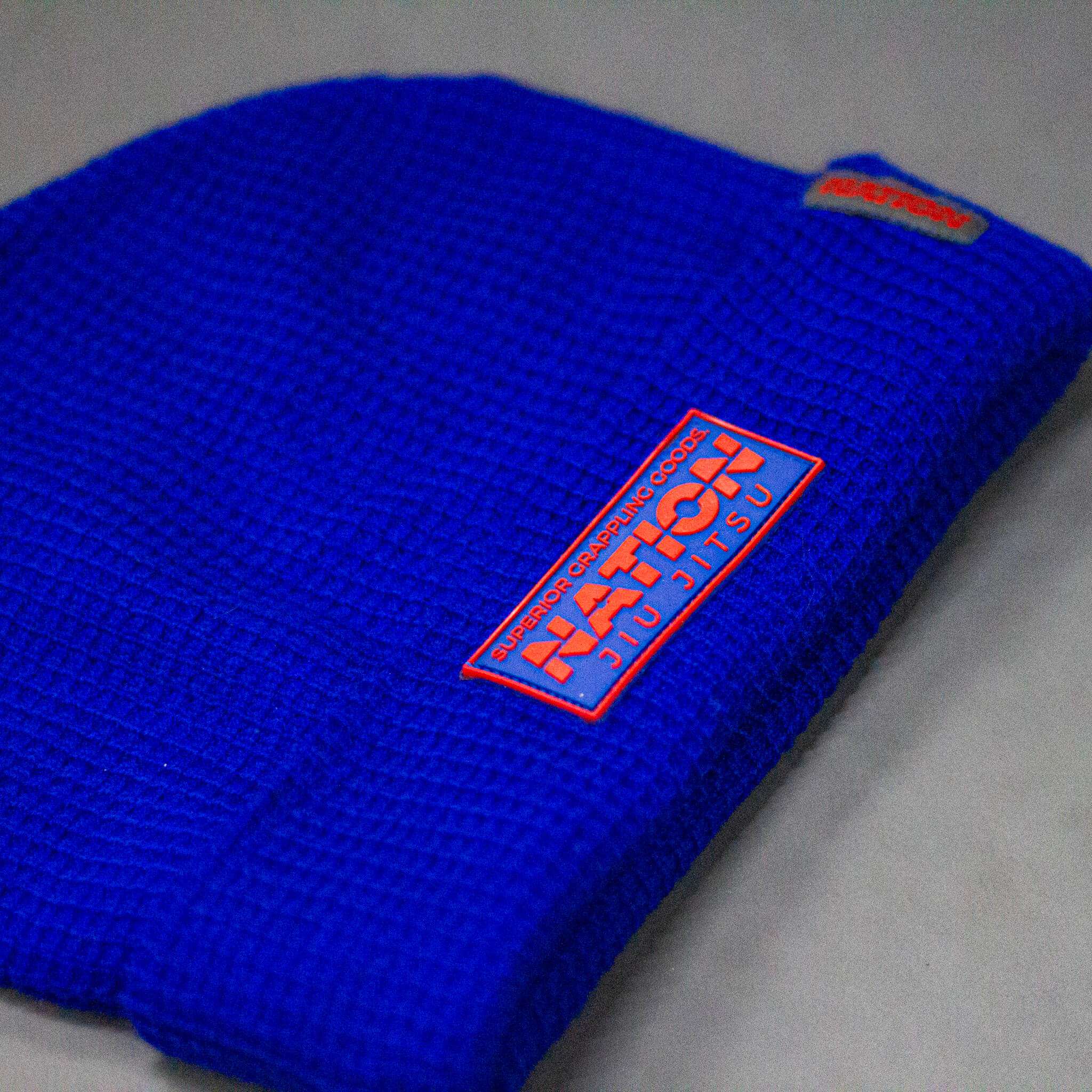 Blue beanie with a red and white logo on a gray background