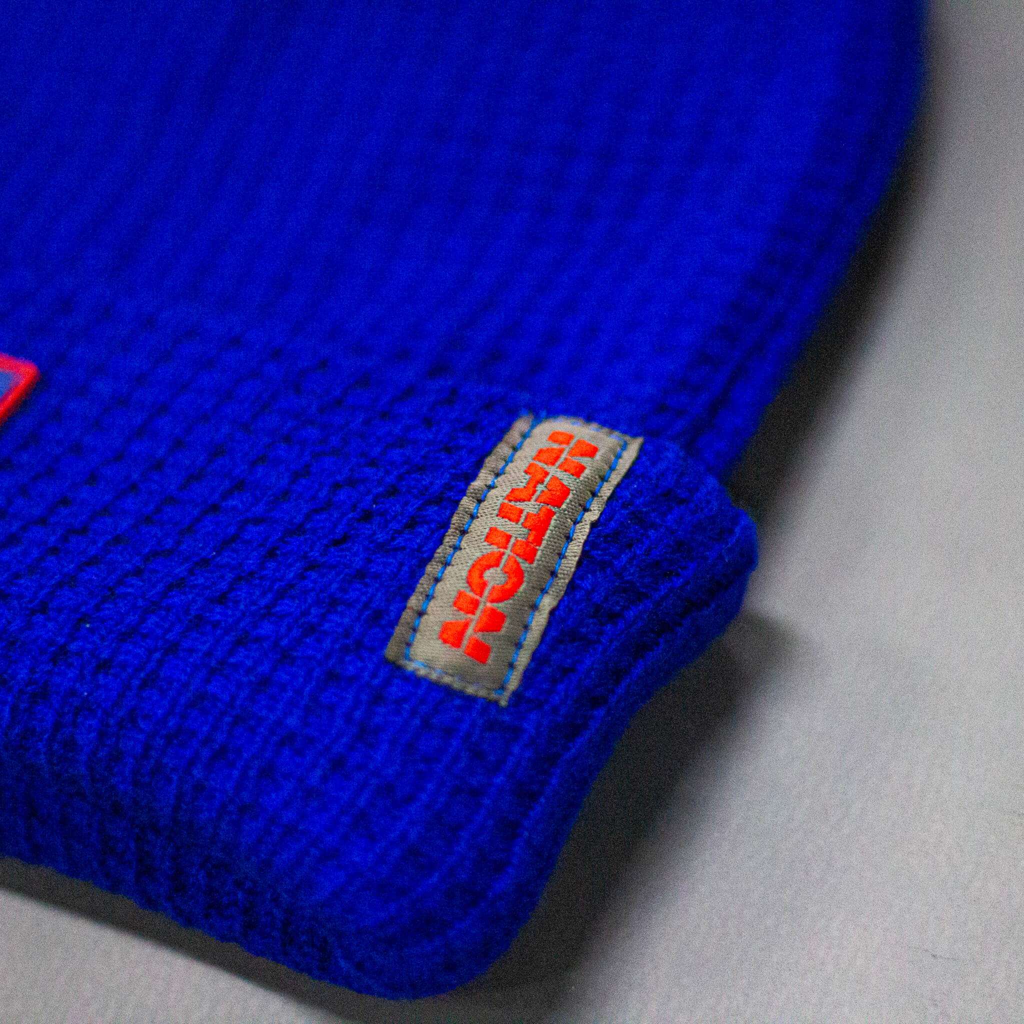 Blue textured fabric with a brand logo on a gray background