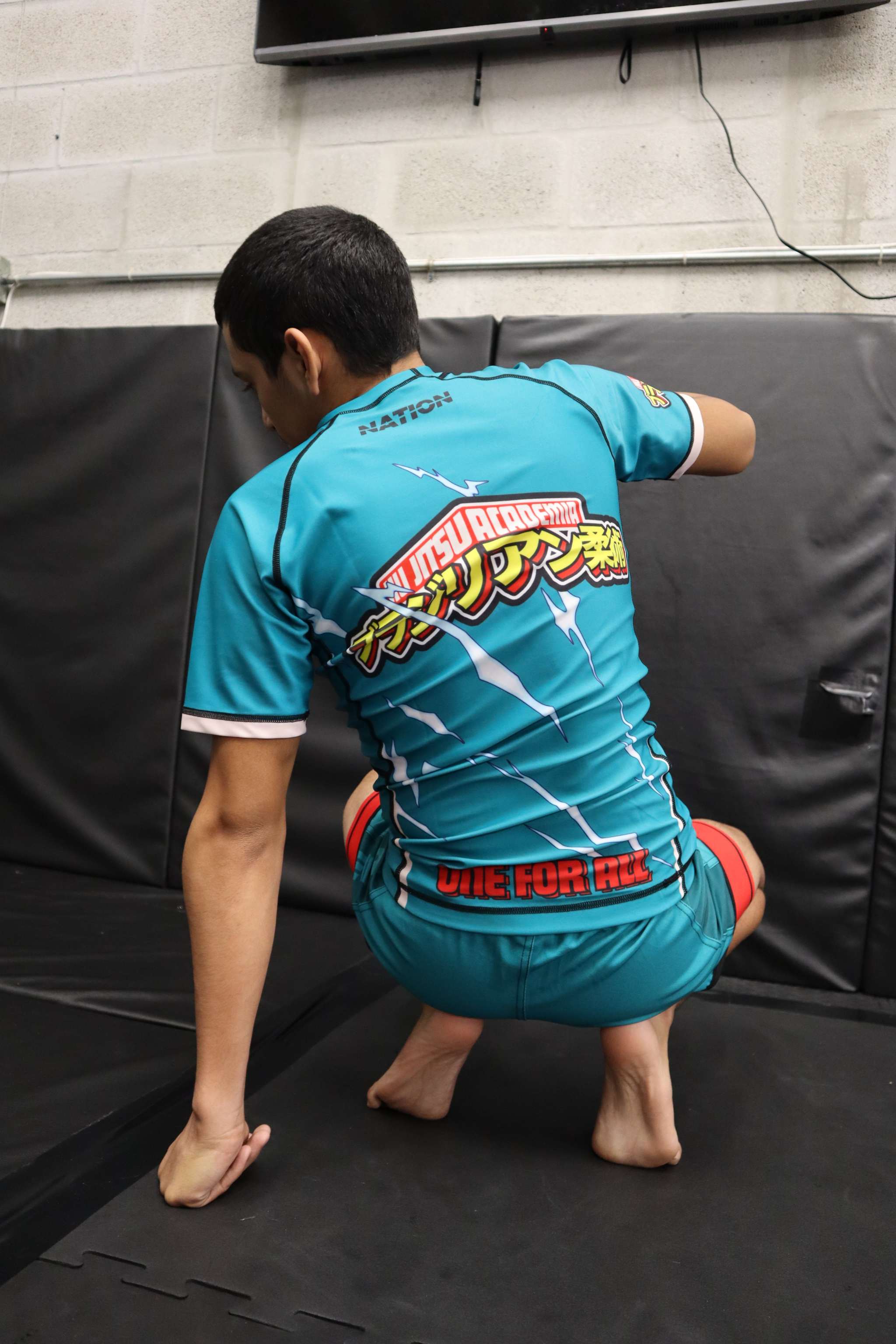 Person wearing a blue athletic outfit with visible branding on a black mat.