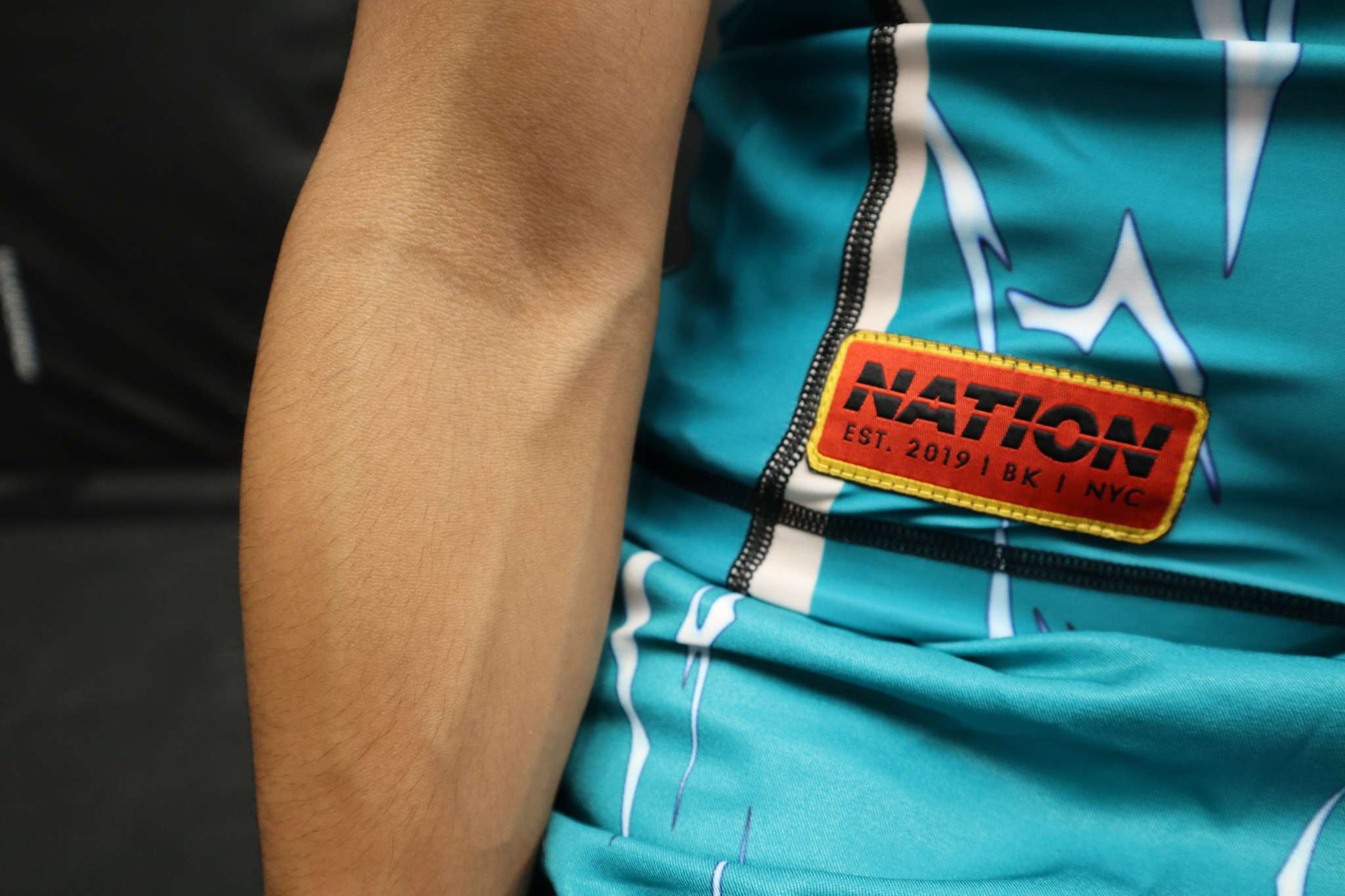 Teal sleeve with a 'Nation' patch on a dark background