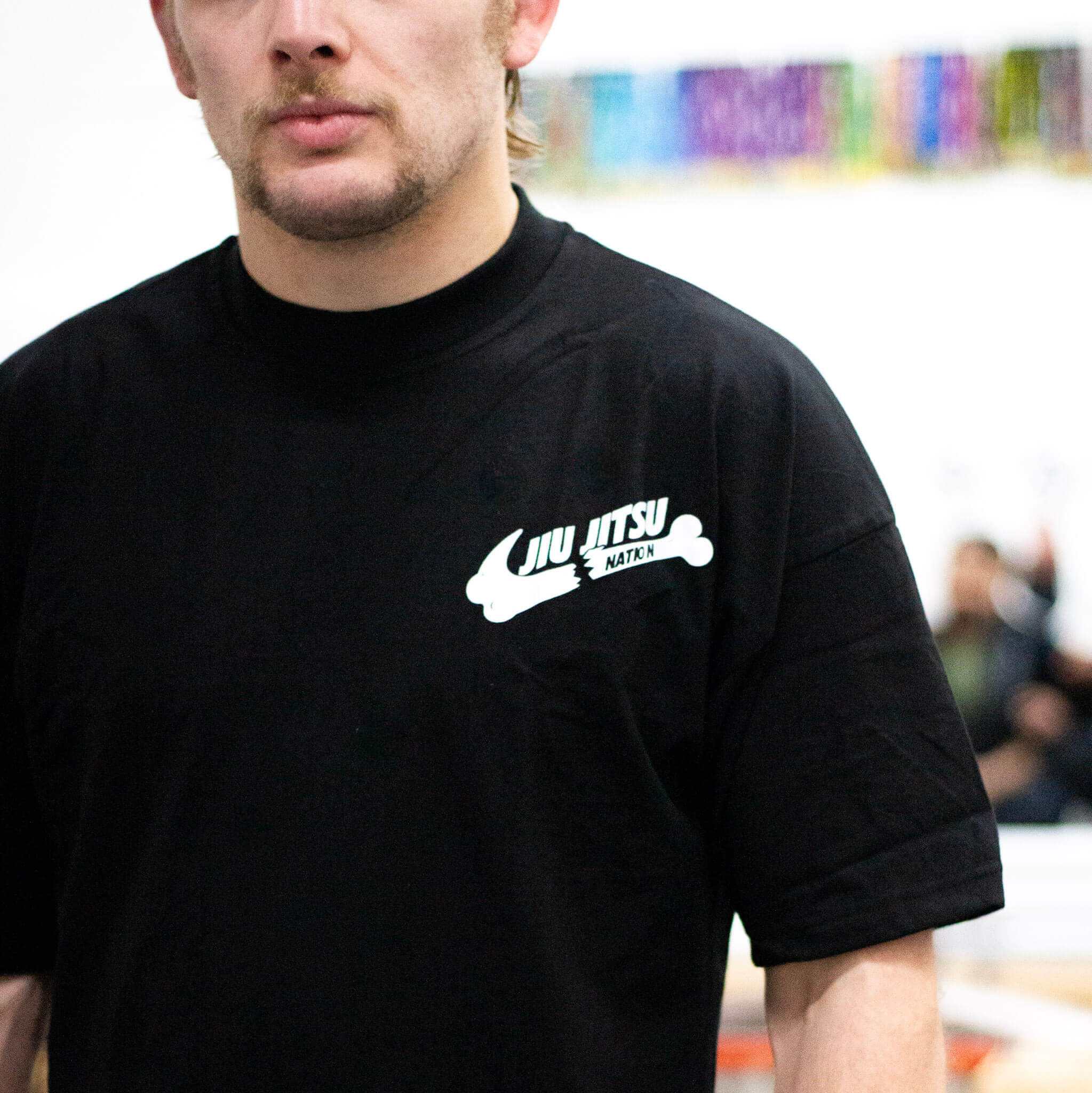 Person wearing a black bjj t-shirt with a white logo in an indoor setting