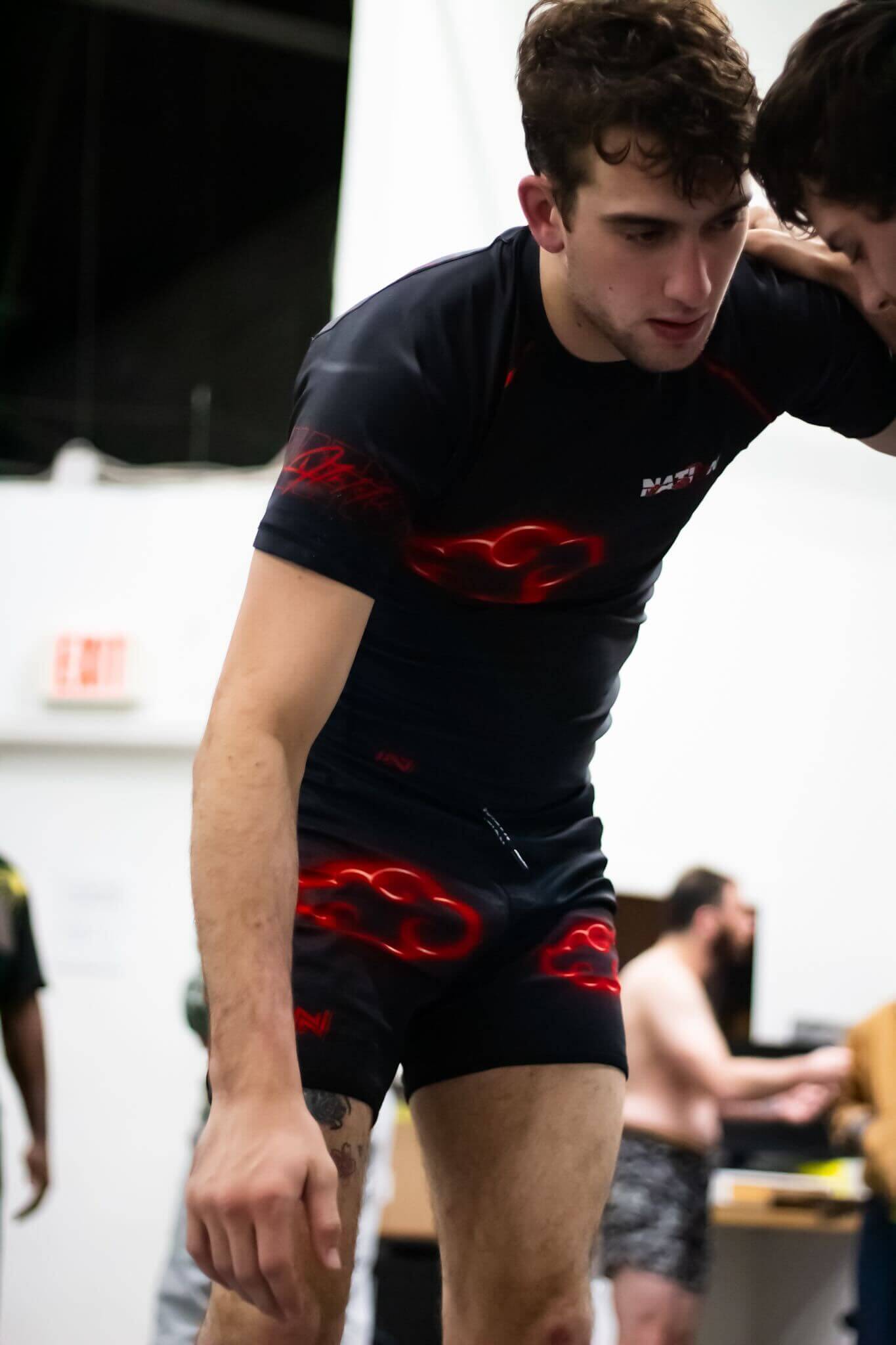 Person wearing black athletic wear with red designs in an indoor setting