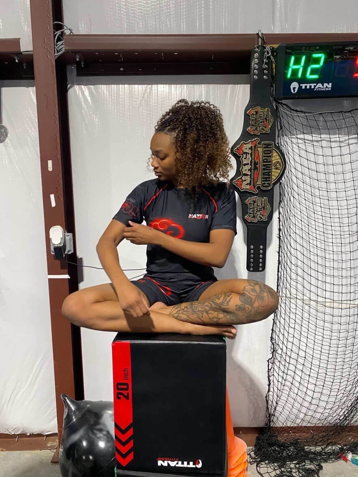 Person sitting on a box with a weightlifting belt and digital display in the background