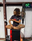 Person sitting on a box with a weightlifting belt and digital display in the background