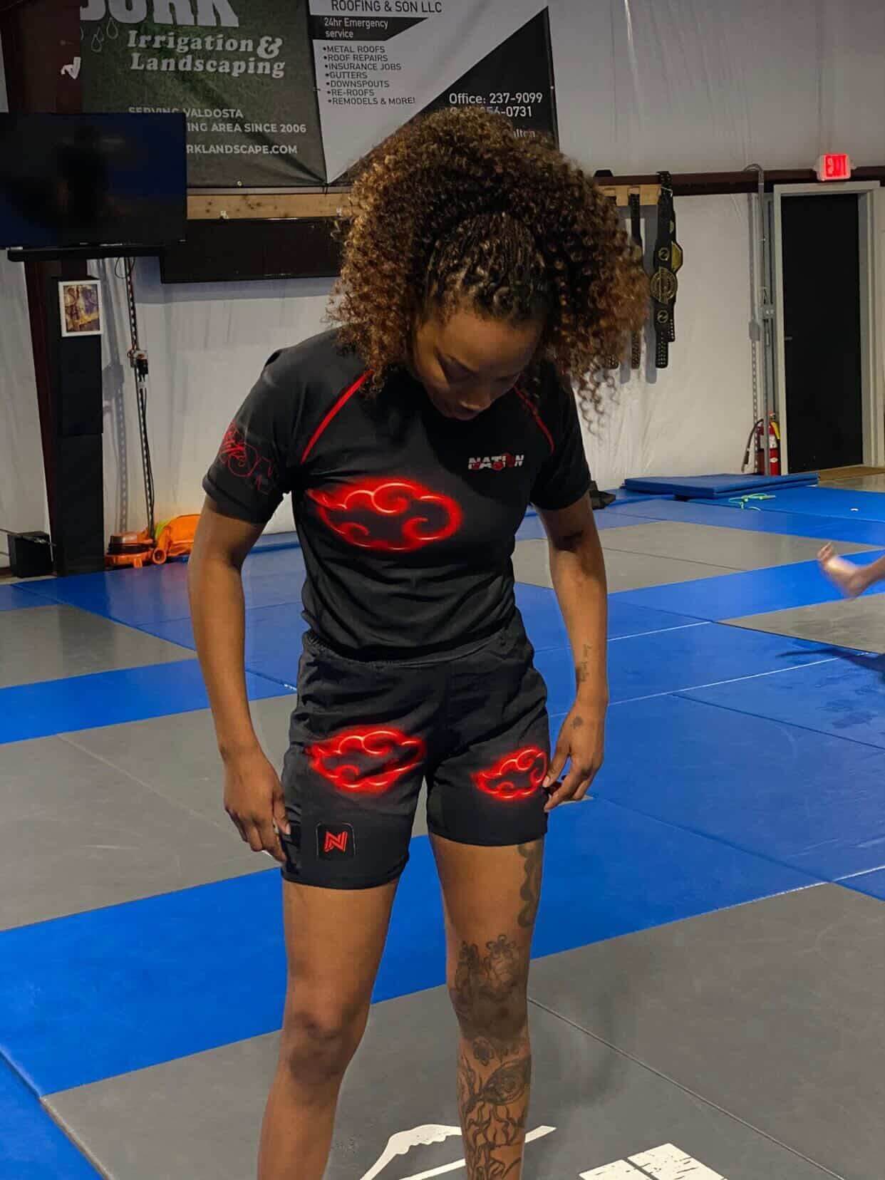 Person wearing a black athletic outfit with red logos in a gym setting
