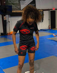 Person wearing a black athletic outfit with red logos in a gym setting