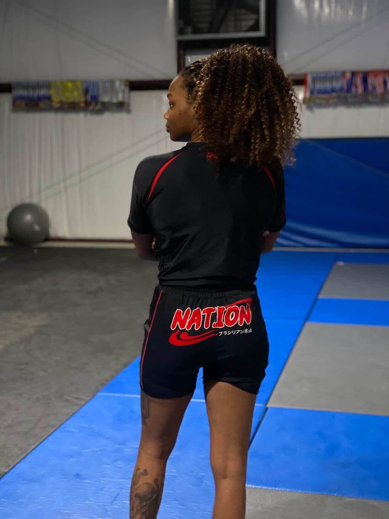 Person wearing a black athletic outfit with 'NATION' branding in a gym setting
