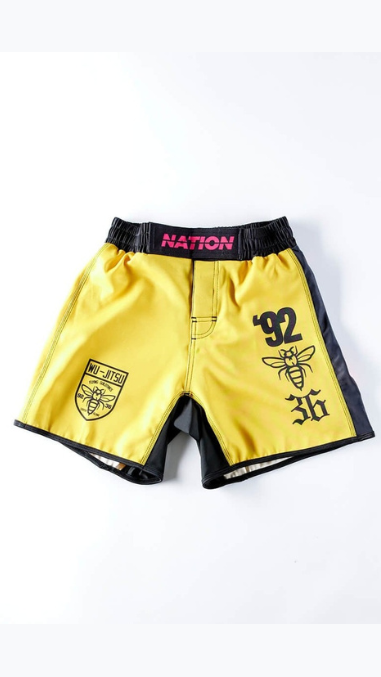 Yellow BJJ grappling shorts with black side panels, featuring '92' and logo graphics, designed for high-performance no-gi Jiu Jitsu.