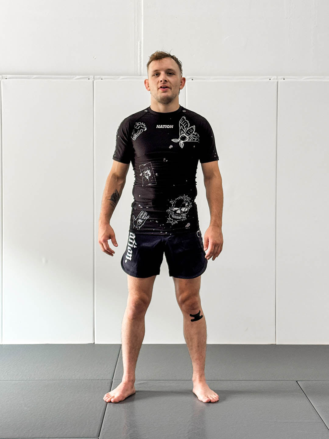 Male wearing Jiu Jitsu Dark Arts BJJ rash guard set in black on mats.