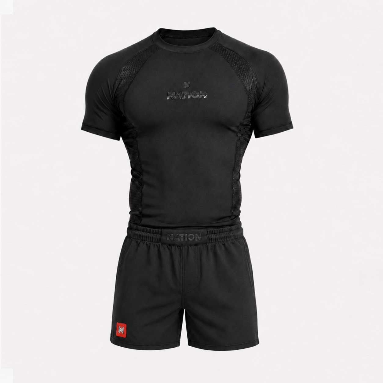 A black athletic compression shirt and matching shorts set on a light gray background. The shirt features a short-sleeve design with mesh panels on the shoulders and sides, a subtle metallic logo on the chest, and an elastic waistband.