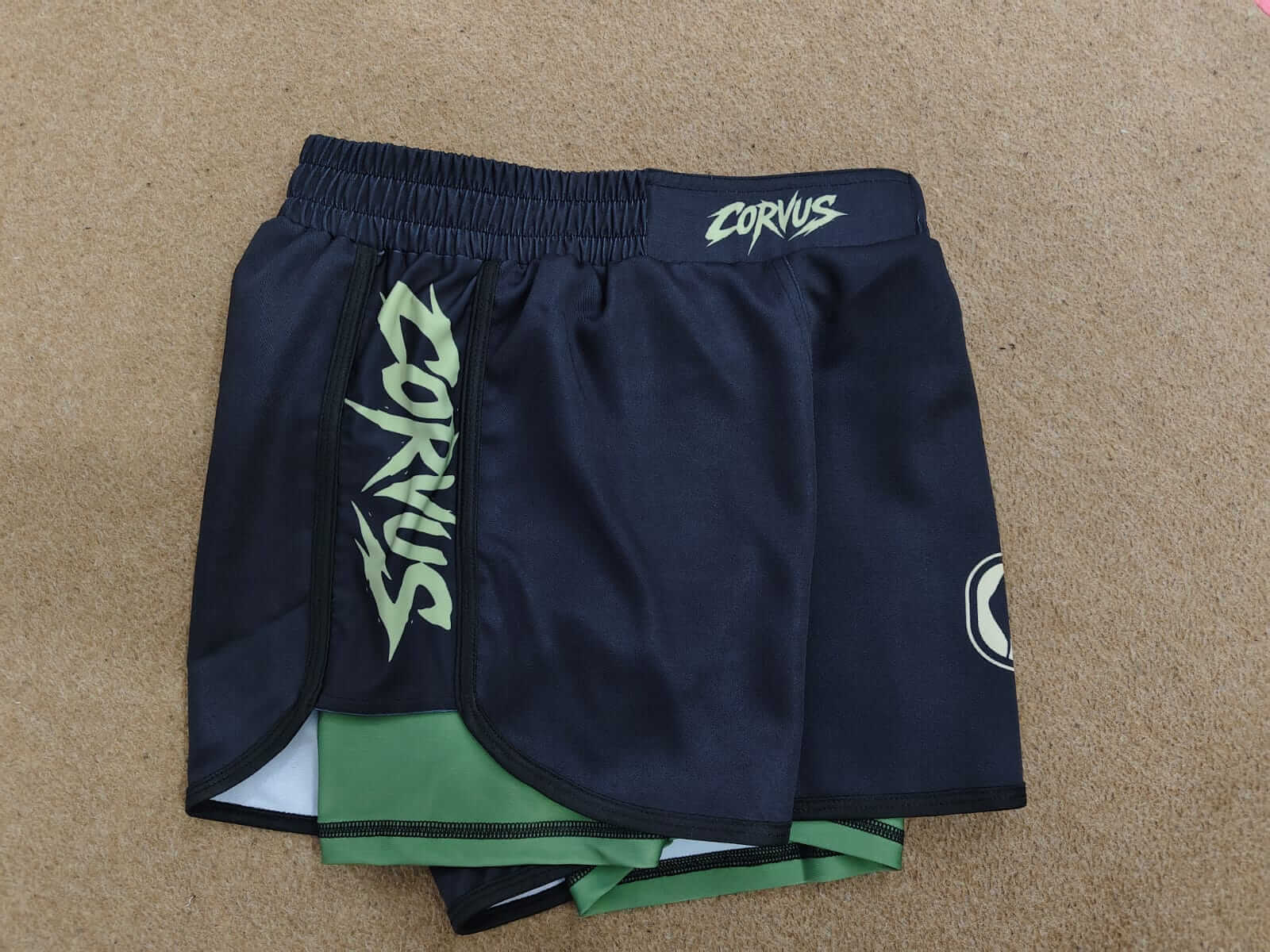 Pair of navy blue shorts with green lining and 'Corvus' branding on a beige background