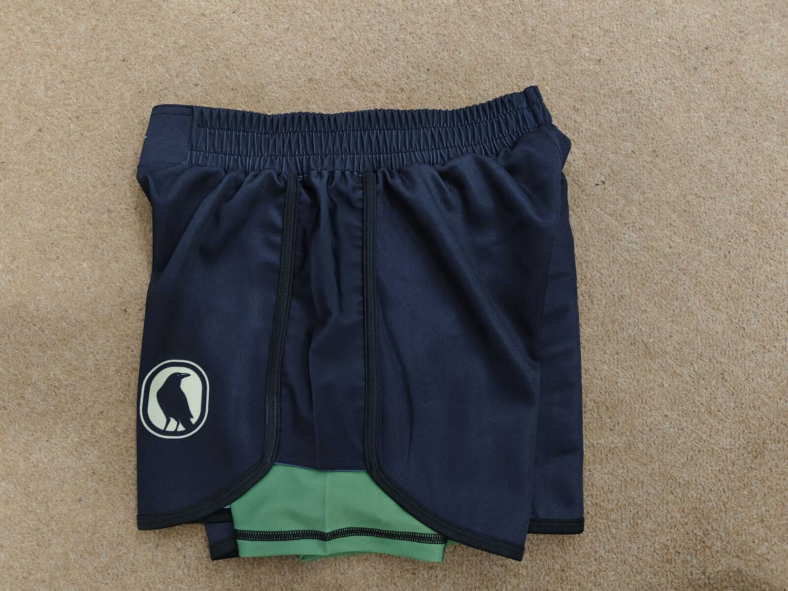 Navy blue shorts with a logo on a beige surface