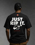 Person wearing a black Bjj design t-shirt with 'Just Rip It' text and graphic on the back, against a gray background.