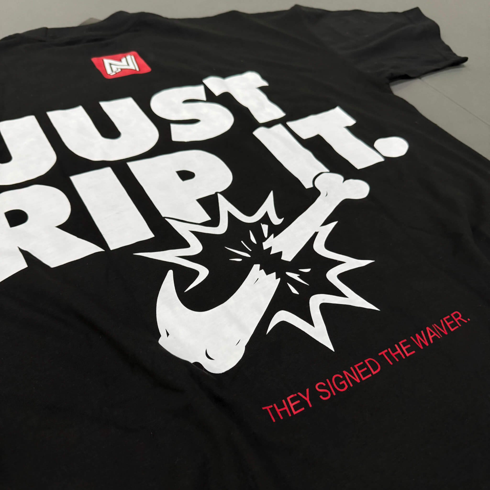 Black t-shirt with white and red text and graphics on a gray surface