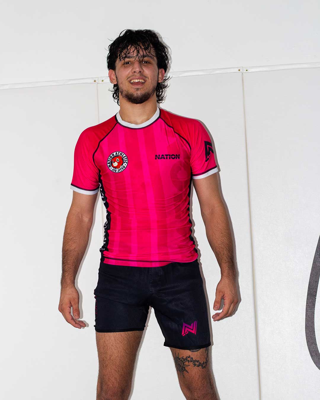 Person wearing a Laney west inspired bjj rash guard and jiu jitsu shorts with visible branding on a white background