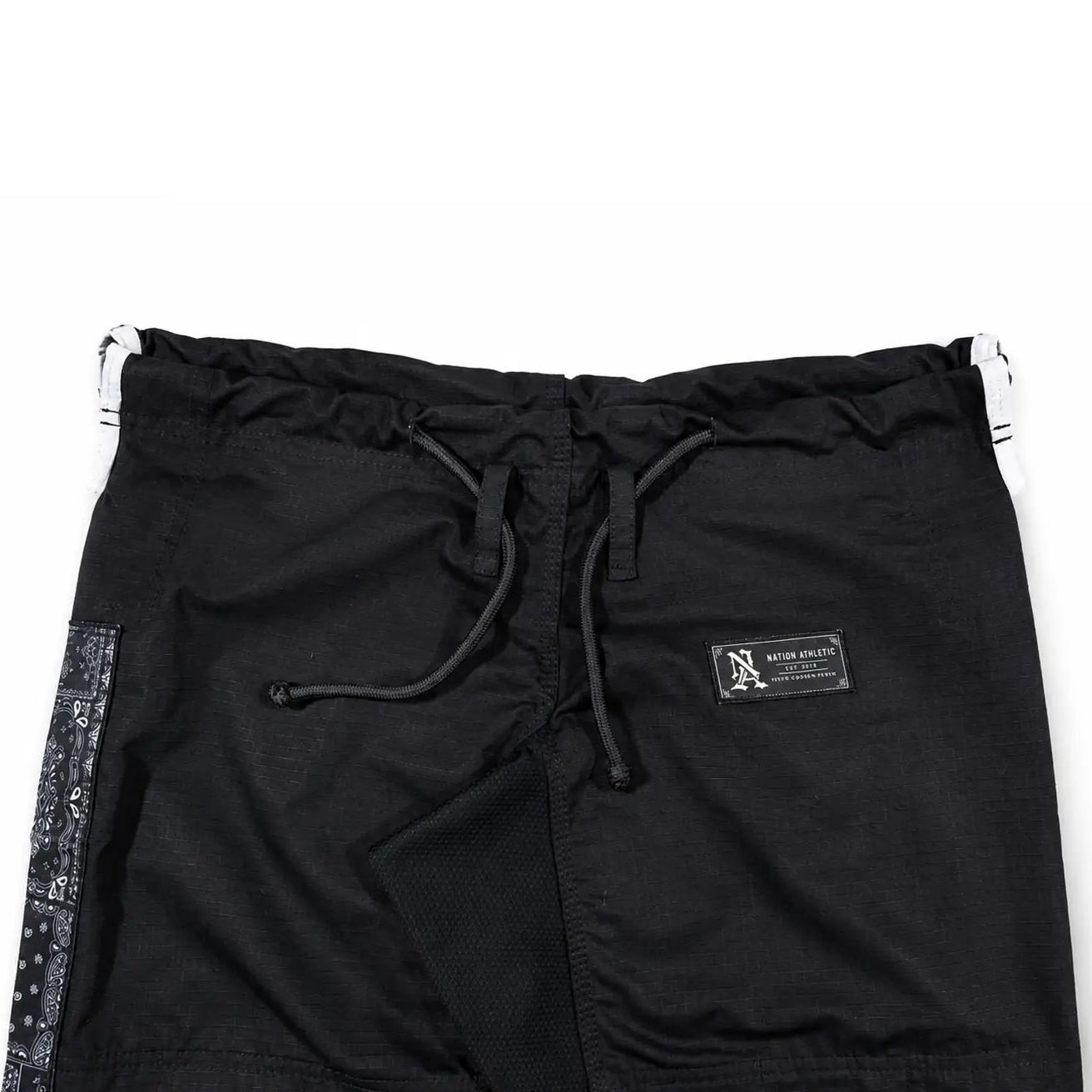 Black athletic bjj gi with a drawstring waist, a small black brand patch on the left hip, and a patterned side stripe, shown flat on a white background.