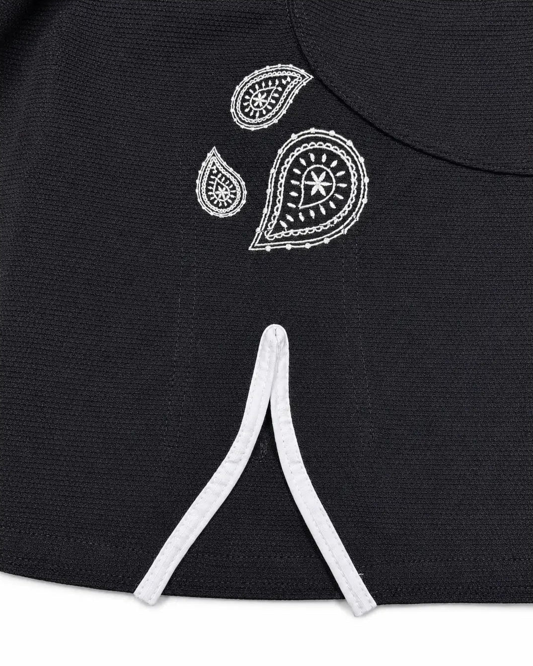 Close-up of a black textured brazilian jiu jitsu gi kimono jacket featuring a white embroidered paisley pattern on the chest and white drawstrings at the waist.