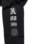 Close-up of a black textured garment sleeve featuring three rectangular patches: a stylized 'NA' patch, a '88' patch, and a 'Parental Advisory' label patch, on a white background.