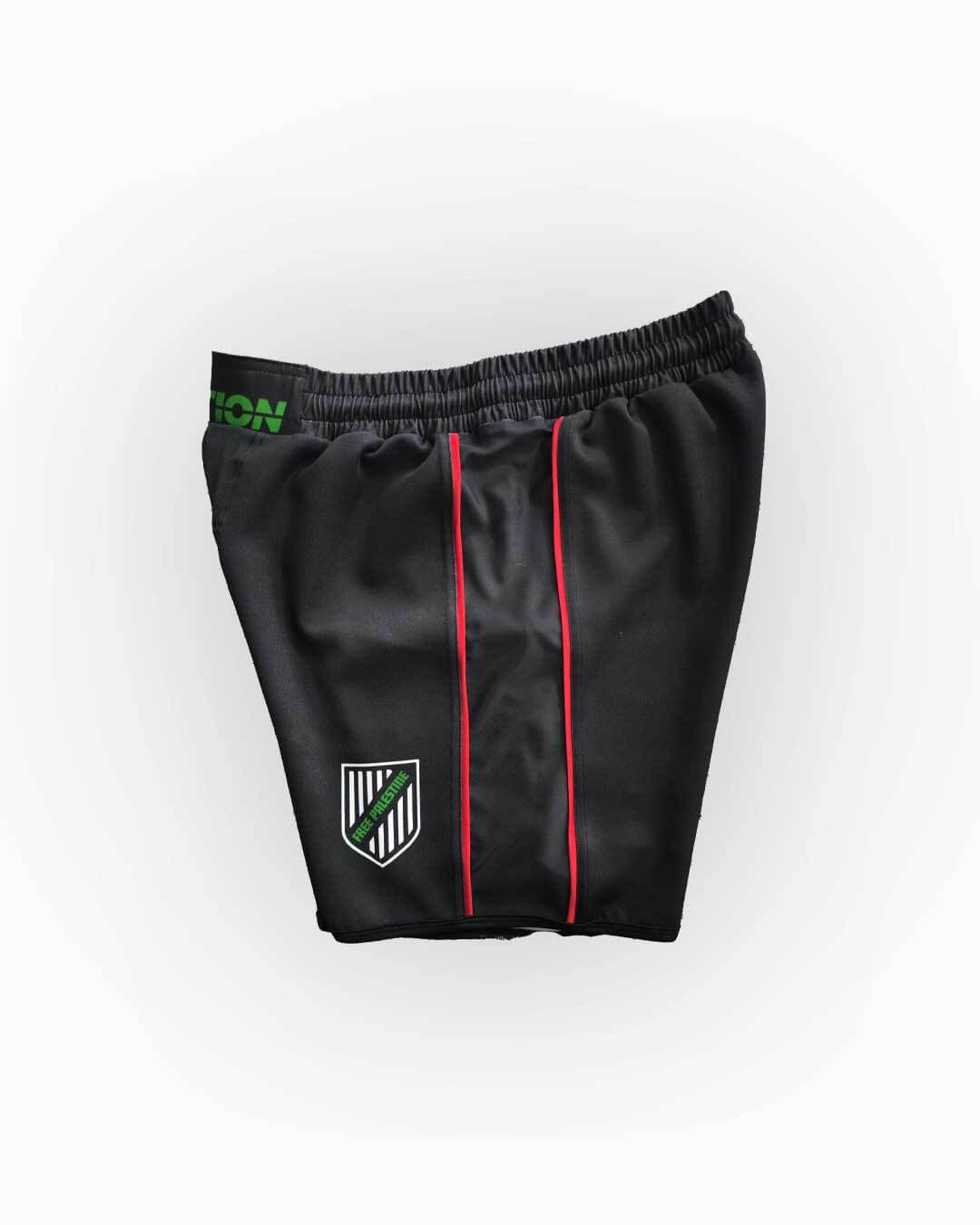 Black athletic shorts with green and red accents on a white background
