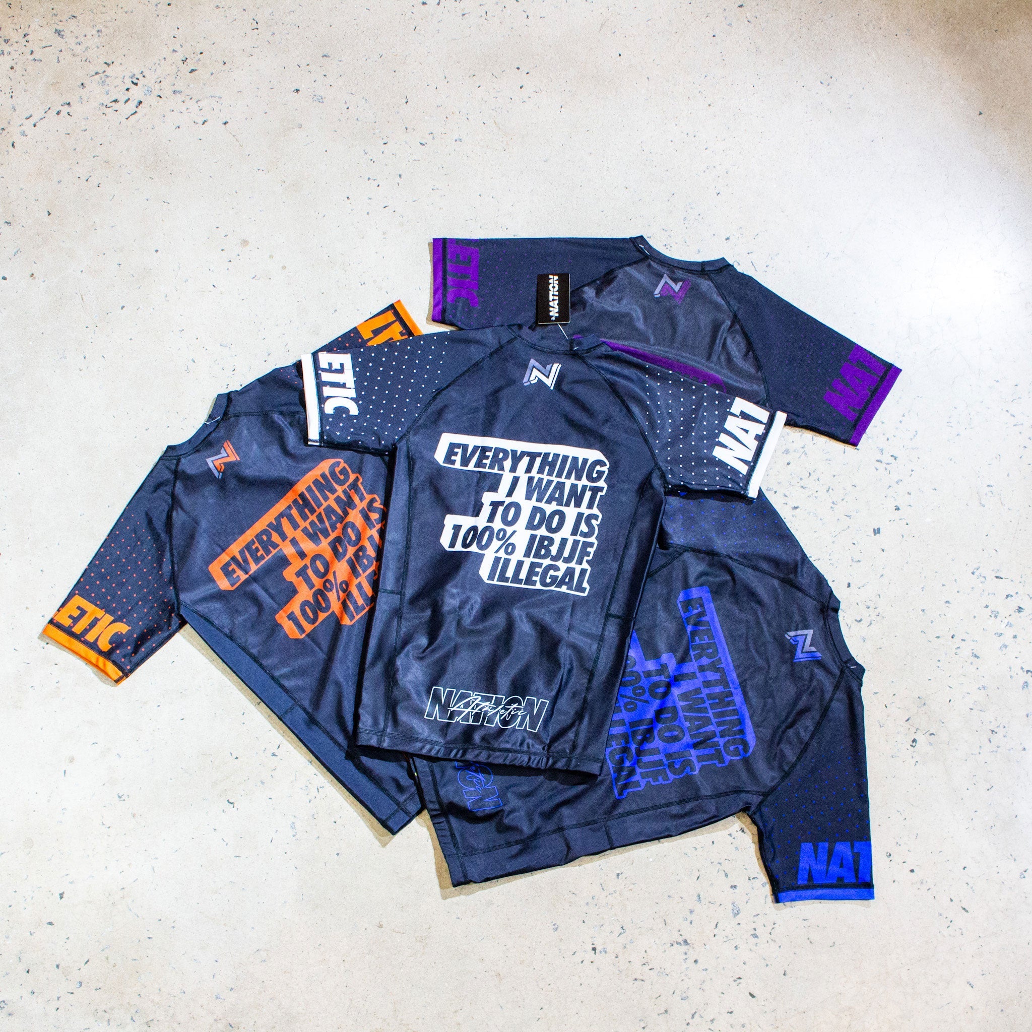 IBJJF Ranked Rash Guard Short Sleeve in multicolor spread out on a floor, showcasing design and text.