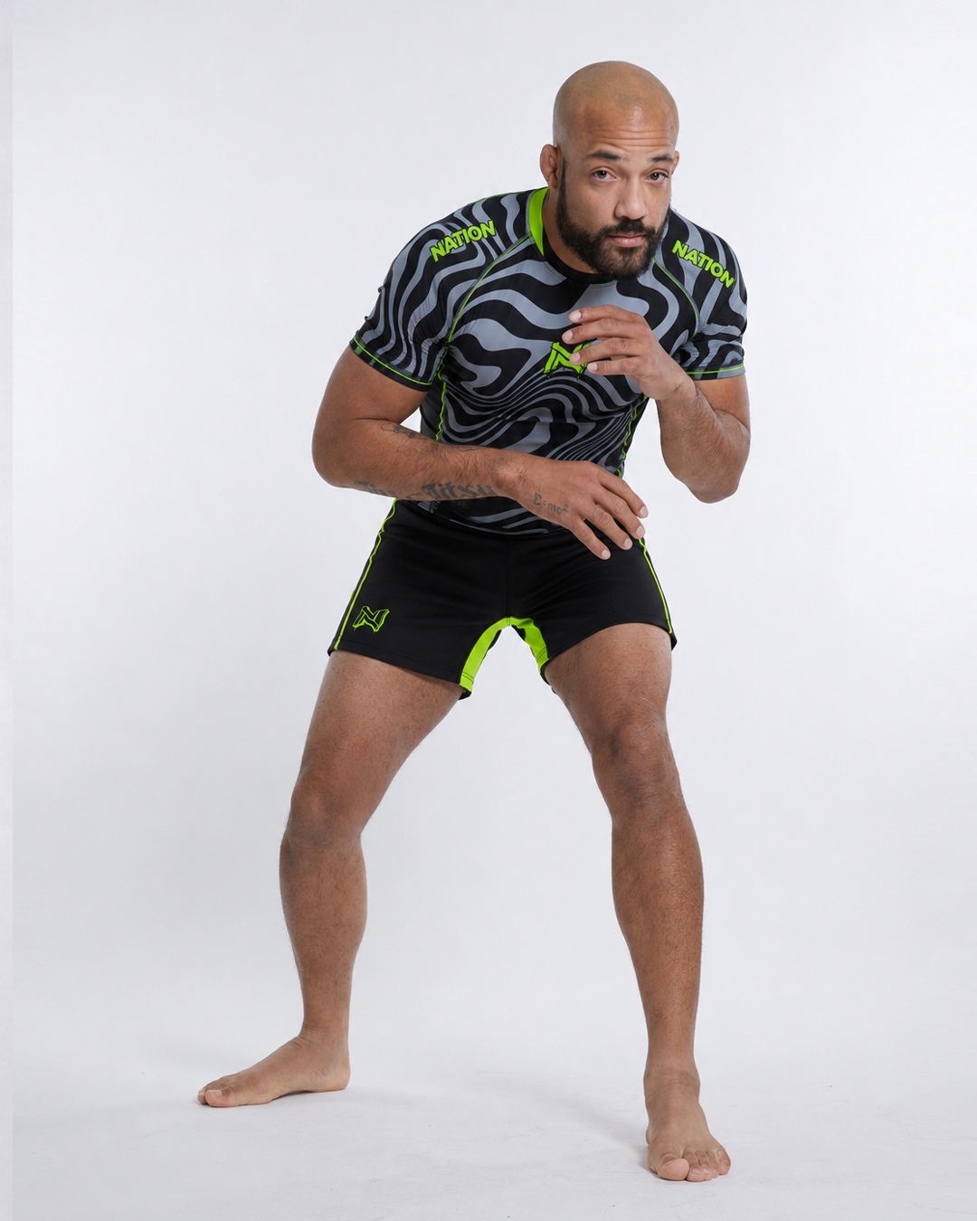 Man wearing a black and gray sports outfit with green accents on a white background